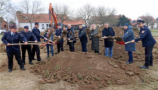 Personen mit Spaten und Schaufeln stehen an einem Erdhaufen.