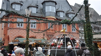 Historisches Fachwerkhaus und Menschen auf einem Weihnachtsmarkt.