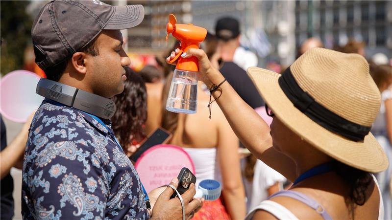 Hitze in Griechenland: Touristen versuchen, sich im Zentrum Athens mit einem kleinen Ventilator, der Wassernebel erzeugt, abzukühlen.