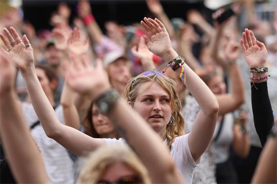 Blick auf Publikum eines Festivals, die Menschen heben die Hände in die Höhe.