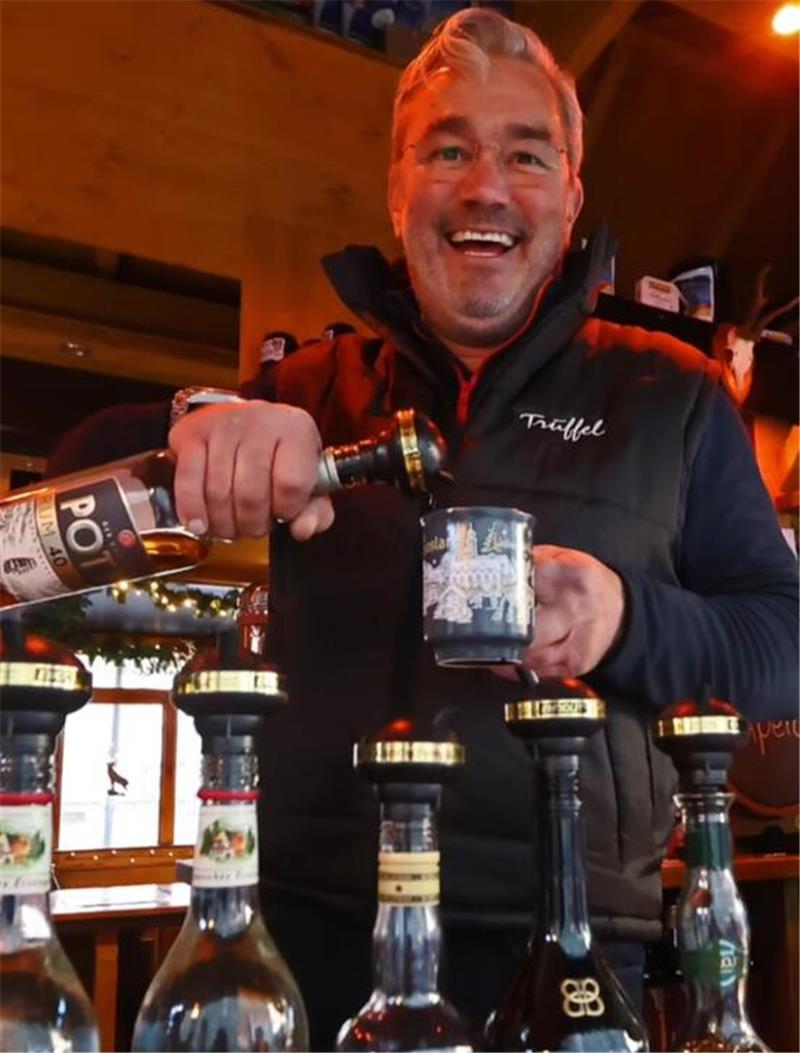Das sagen die Schausteller zum Goslarer Weihnachtsmarkt Person in schwarzer Weste mit Schriftzug "Trüffel" gießt aus einer Flasche in einen Becher, davor stehen mehrere Spirituosenflaschen auf einer Theke.