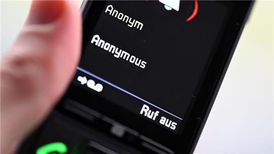 ILLUSTRATION - Ein Mann hält ein Festnetz-Telefon, auf dem ein anonymer Anruf eingeht (gestellte Szene). 