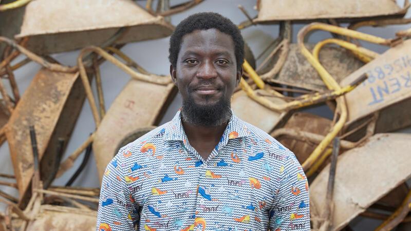 Ibrahim Mahama 2021 in Leipzig vor seiner Kunstinstallation „Vanishing Points“ mit hundert benutzten Schubkarren ghanaischer Wanderarbeiter, die dafür im Tausch neue bekamen. Foto: Punctum/Alexander Schmidt
