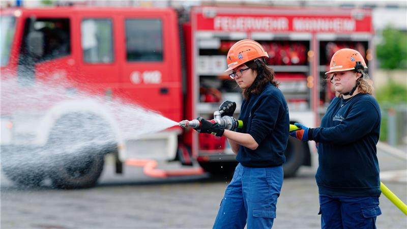 Ilias (links) und Annabella, Mitglieder der Jugendfeuerwehr in Mannheim, halten bei einer Übung einen Feuerwehrschlauch in den Händen.