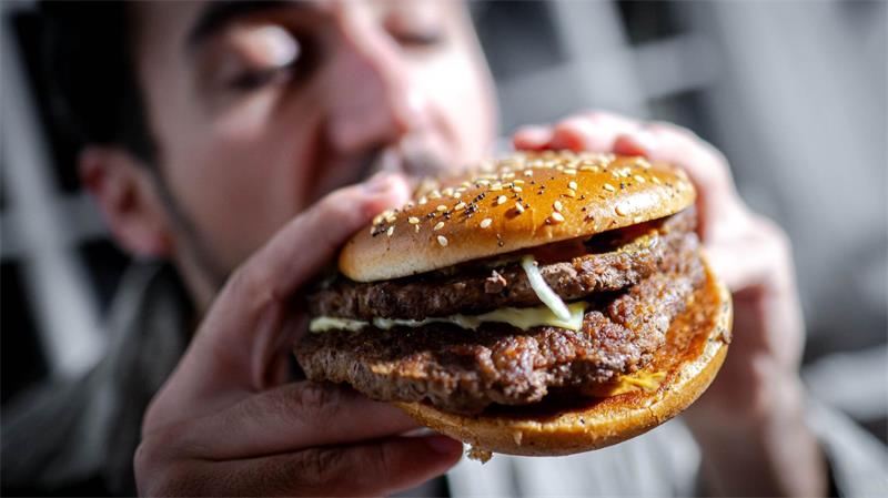 Wie Künstliche Intelligenz den optimalen Burger designt Illustration - Ein Mann beißt in einen Burger