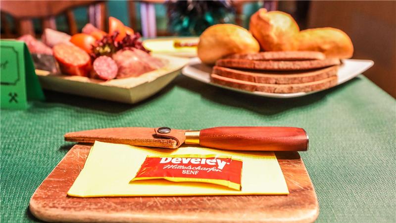 Bergdankfest im Oberharz: Tradition lebt trotz eisiger Kälte Brötchen, Brot, Wurst und ein Messer auf einem Holzbrett.