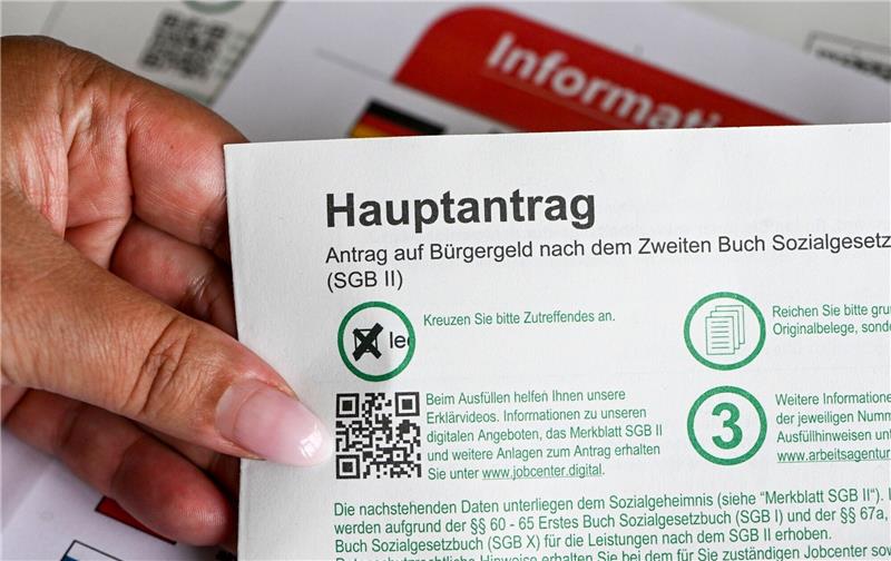 Bildungsanbieter kritisiert Jobcenter Im Jobcenter hält eine Frau einen Antrag auf Bürgergeld in der Hand.