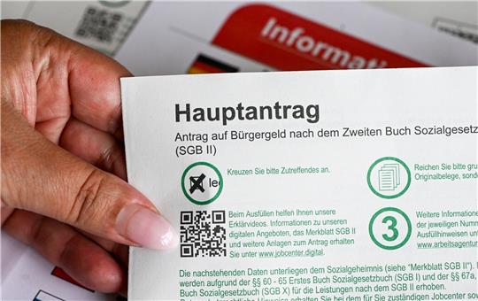Im Jobcenter hält eine Frau einen Antrag auf Bürgergeld in der Hand.