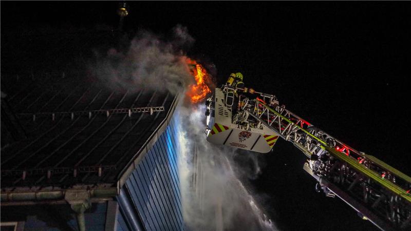 Feuerwehrleute löschen von einer Drehleiter aus die Flammen an der Fassade der Marktkirche.