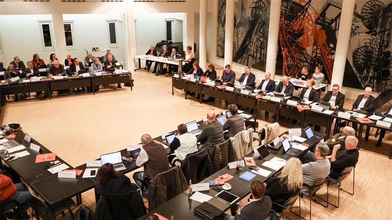 Blick in den Kreistagssaal. Die Abgeordneten sitzen an Tischen nebeneinander.