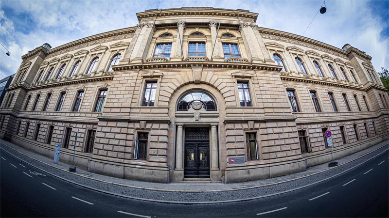 Breit aufgenommene Fassade eines historischen mehrstöckigen Gebäudes mit Säulen und verzierten Fenstern