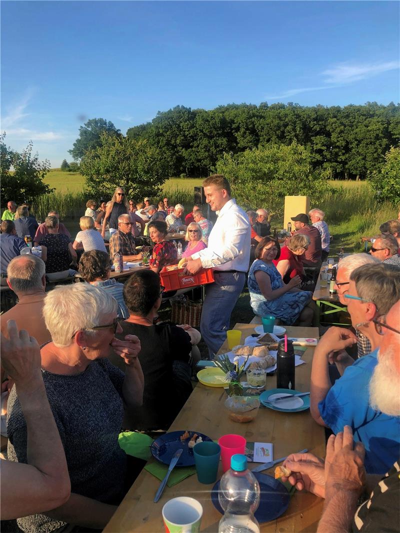 Im Licht der milden Sommerabendsonne: Harzbrot-Bäckermeister Tobias Rinn verteilt während der Genossenschafts-Gründungsfeier auf dem Gelände der Bäckerei Braun Brot und Baguette an die Harzbrot-Mitglieder. Foto: Stade