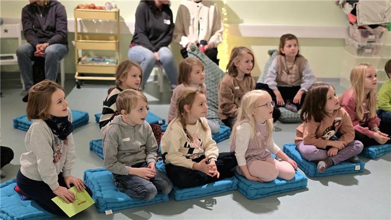 Kinder sitzen auf blauen Kissen auf den Boden.
