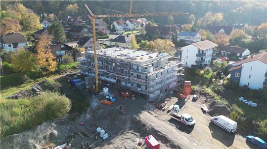 Im November, als die Luftaufnahme entstanden ist, wird noch am Rohbau des Mehrfamilienhauses gearbeitet. Inzwischen läuft der Innenausbau.