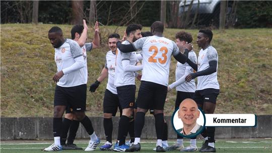 Fußballspieler in weißen Trikots feiern auf einem Spielfeld mit Kunstrasen.