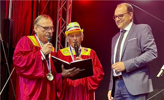 Drei Männer stehen auf einer Bühne.