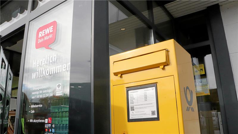 Ein Briefkasten steht vor einer Rewe-Filiale