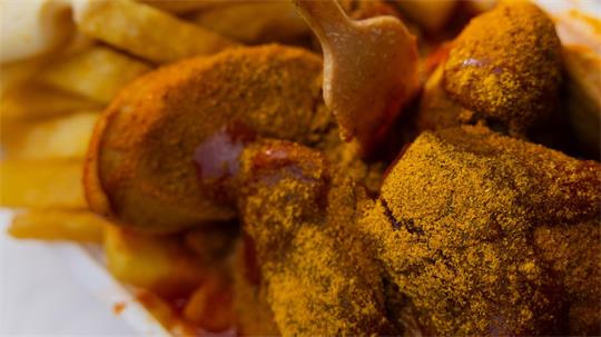 Nahaufnahme von paniertem und mit Curry bestreutem frittiertem Essen neben Pommes frites