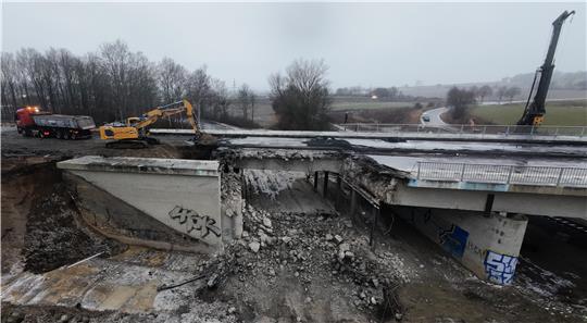 Im Widerlagerbereich einer Brücke steht ein Bagger und belädt einen Laster.