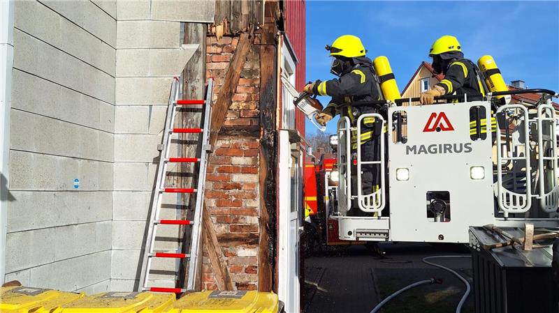 Im Zuge der Brandbekämpfung müssen die Einsatzkräfte einen Teil der Außenfassade des Gebäudes entfernen.