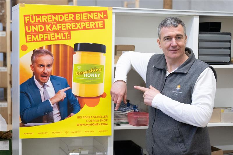 Honig-Streit mit Böhmermann geht in nächste Instanz Imker Rico Heinzig neben einem Plakat mit dem Foto des Moderators Jan Böhmermann.