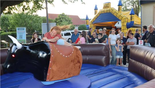 Eine Frau fällt beim Bullriding vom Elektro-Bullen. 