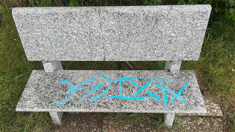 Das Bild zeigt eine Bank aus Stein, deren Sitzfläche mit Farbe beschmiert ist. 