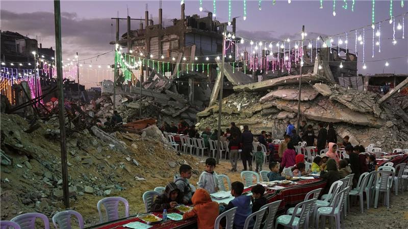 In Chan Junis sitzen Palästinenser an einem langen Tisch inmitten von zerstörten Gebäuden zum Fastenbrechen (Iftar) während des muslimischen heiligen Monats Ramadan.