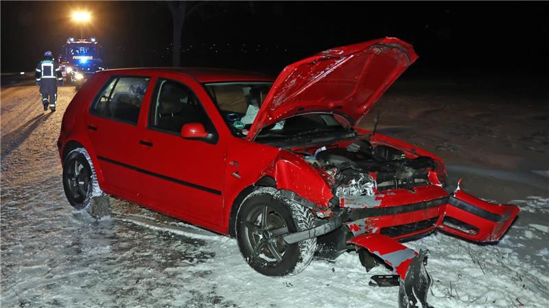 Ein kaputtes rotes Auto mit offener Motorhaube steht im Schnee.