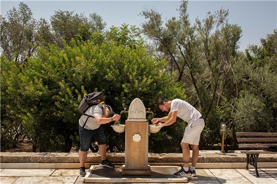 In Griechenland ist es dieser Tage sehr heiß. Touristen erfrischen sich an einem öffentlichen Trinkbrunnern.