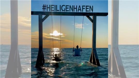 In Heiligenhafen steht sie im flachen Ostseewasser. Der Schriftzug „#Heiligenhafen“ zeigt, mit welchem Schlagwort die an der Schaukel gemachten Bilder oder Videos – hier zu sehen eins auf „TikTok“ – hochgeladen werden sollten. Screenshot: GZ