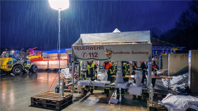 In Schlüsselfeld im Landkreis Bamberg befüllen Feuerwehrleute Sandsäcke.