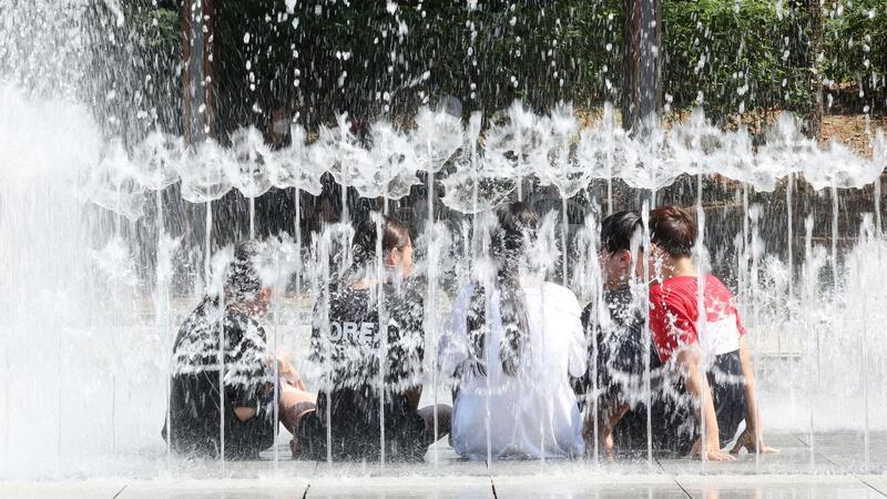 In Südkorea herrscht eine Hitzewelle. Um kühlen Kopf zu bewahren, erfrischen sich diese Schülerinnen und Schüler kurzerhand in einem Brunnen.
