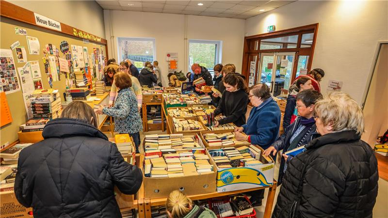 Das Bild zeigt die Stadtbibliothek in Clausthal-Zellerfeld. Auf den Tischen stehen volle Kartons mit Büchern. Viele Menschen stehen an den Kisten und stöbern darin.