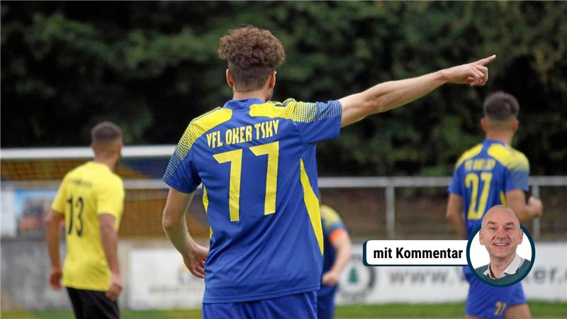 Fußballspieler mit blau-gelbem Trikot und der Nummer 77 zeigt mit ausgestrecktem Arm nach rechts, weitere Spieler im Hintergrund auf dem Spielfeld.