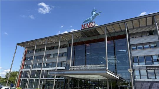 Ein Gebäude mit einer sehr großen und gläsernen Fensterfront. Auf dem Dacht trohnt die Statue eines blauen Einhorns.