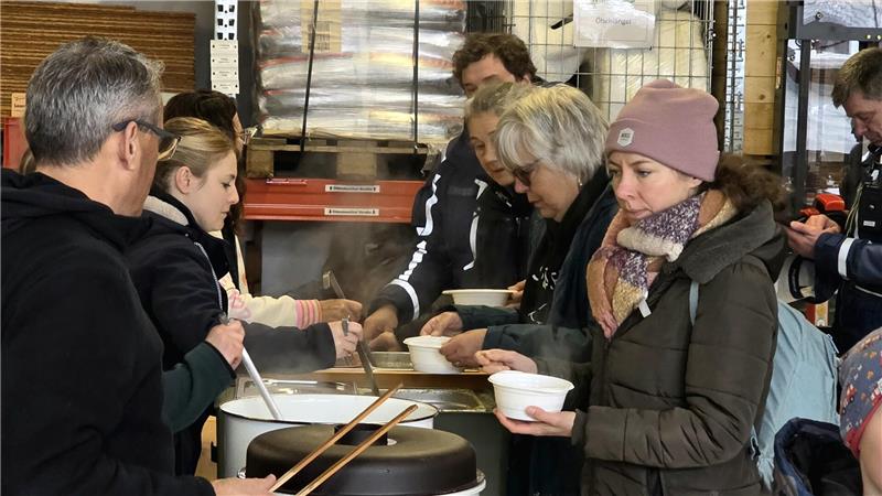 „Müllboss“ in Goslar: Skier, Auspuff und „Drogen“ im Müll entdeckt Menschen stehen in einer Schlange in einer Halle und erhalten aus großen Behältern dampfende Suppe in Schalen