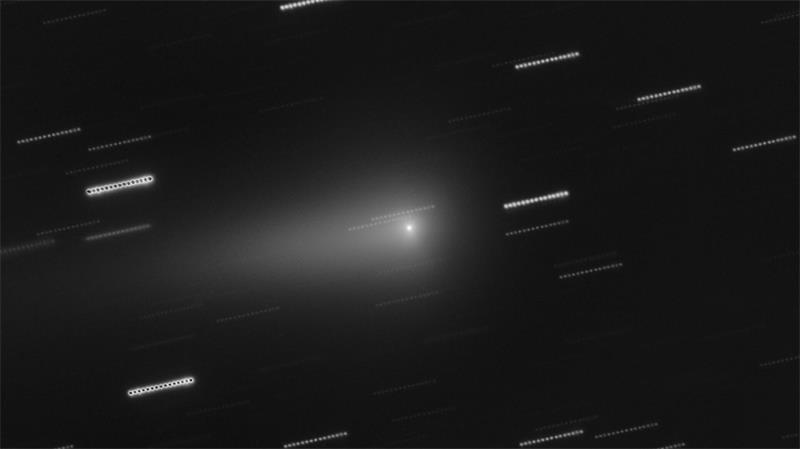 In der Mitte ist der Komet 3I/Atlas zu sehen. Die Sterne im Hintergrund erscheinen als Lichtspuren, weil die Aufnahme aus mehreren nacheinander aufgenommen Einzelbildern zusammengesetzt wurde.
