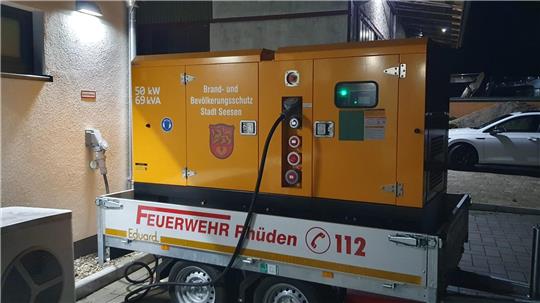 Orangefarbenes Notstromaggregat auf einem silbernen Anhänger mit der Aufschrift "Feuerwehr Rhüden 112".