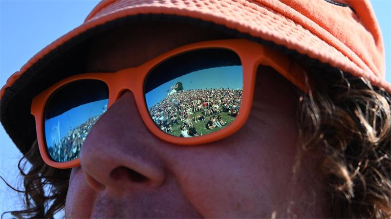 In der Sonnenbrille eines Besuchers spiegelt sich bei dem Musikfestival „Das Fest“ der gut gefüllte Hügel auf der Günther-Klotz-Anlage in Karlsruhe.