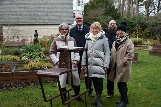 Drei Frauen und zwei Männer stehen hinter einem Lesestuhl.