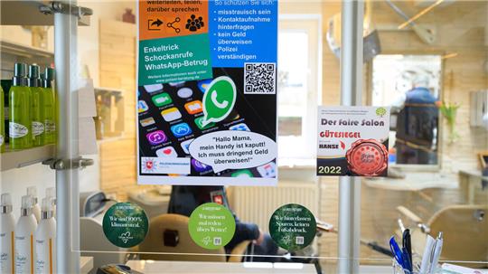In einem Friseursalon in Lüneburg warnt die Polizei mit einem Plakat über Betrugsmaschen.