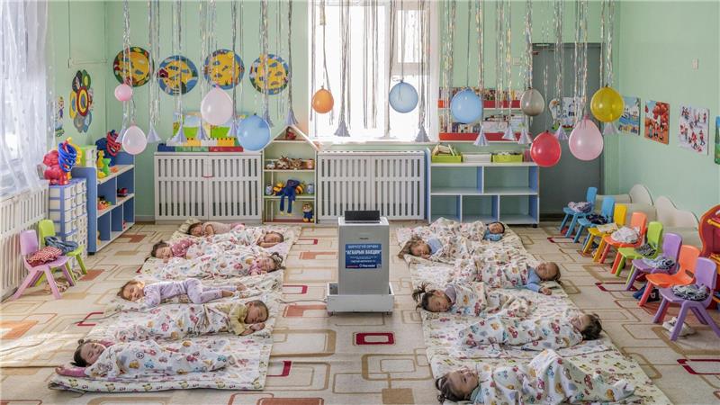 In einem Kindergarten in Ulaanbaatar, der Hauptstadt der Mongolei, liegen Kinder auf dem Boden um einen aufgestellten Luftfilter herum, der die Schadstoffkonzentration senken soll.
