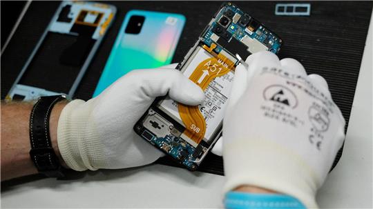 In einer Werkstatt wird ein altes Smartphone wiederaufbereitet. 