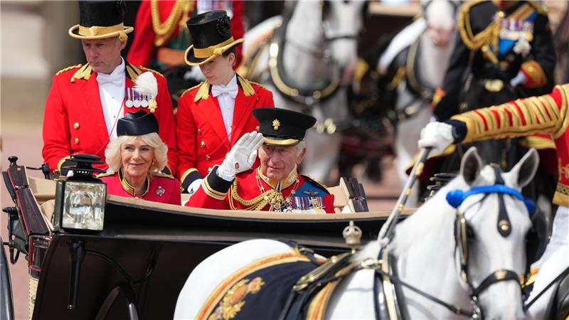In einer offenen Kutsche fährt das britische Königspaar durch London.