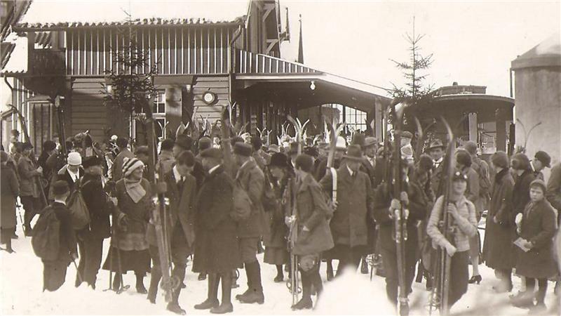 Das historische Foto zeigt viele Menschen mit Skiern.