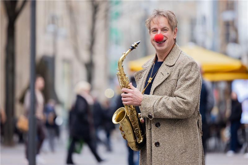 Ingolf Lück, Schauspieler, Moderator und  Komiker, steht mit seinem Saxophon in Kölns  Innenstadt.