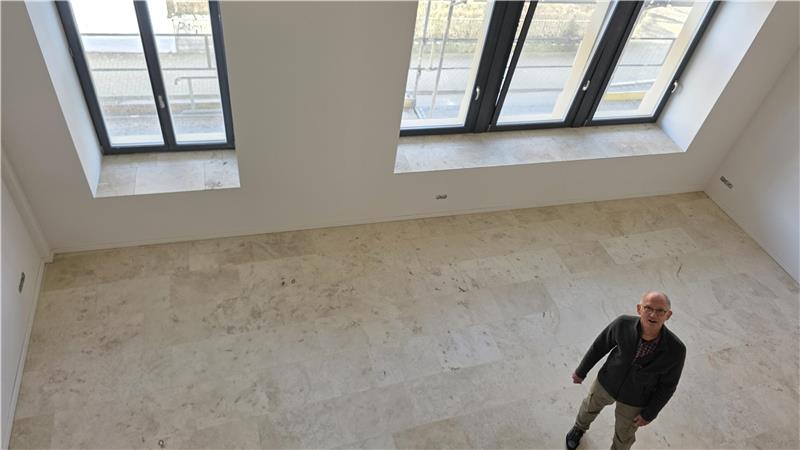 Leerer Raum mit großen Fenstern und einer Person, die auf dem Boden steht