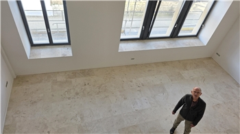 Leerer Raum mit großen Fenstern und einer Person, die auf dem Boden steht