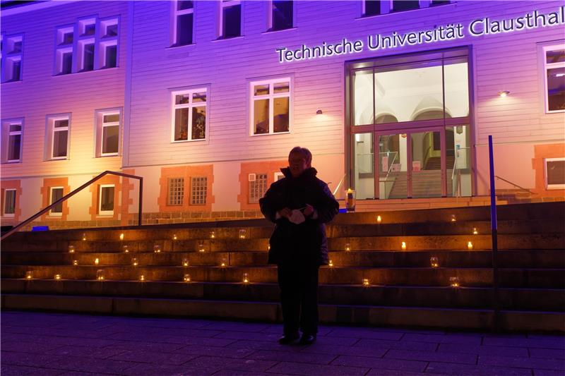 Iris Künstel steht vor dem in den Farben blau und gelb der Ukraine leuchtenden Hauptgebäude der Uni und hat gerade wie viele weitere Besucherinnen des Weltgebetstags der Frauen eine Kerze auf die Treppe gestellt. Fotos: Hörseljau